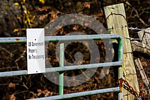 US Government Property sign on locked gate with thick woods in b