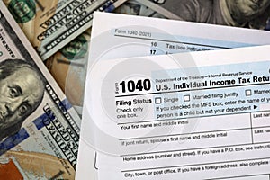 US 1040 individual income tax return form with 100 dollar bills.