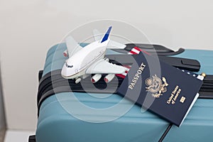 US passport lies on a suitcase next to a US flag and a toy airplane.Travel concept