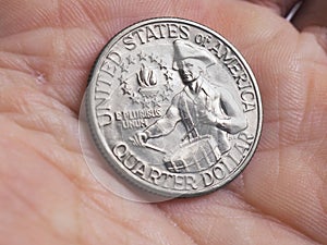 The US quarter dollar coin with drummer lies in a man`s palm close-up. Illustration on the theme of American patriotism and