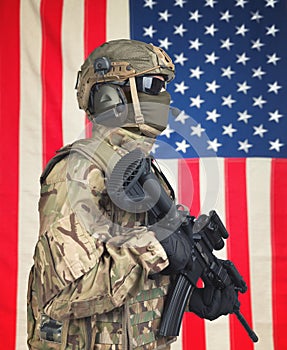 US soldier with machine gun in hands and American flag on background