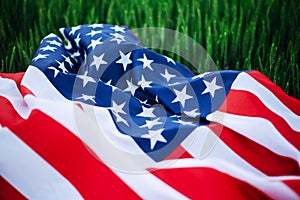 USA american flag lays casually on the spikelets on the green wheat field. Patriotic holiday celebration. United States