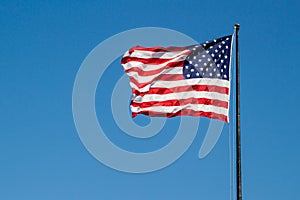 USA American flag waving in the wind on clear blue sky in background