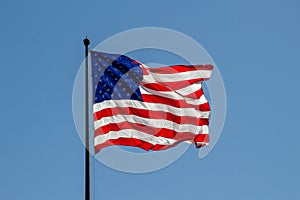 USA American flag waving in the wind on clear blue sky in background