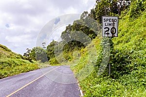 USA American style white Speed Limit 20 mph road sign with dirt rust rain stains overgrown in jungle. Pohnpei,Micronesia, Oceania.