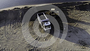 USA, California - May 20, 2022: excavator digging and loading sand into dump truck at river bank. Scene. Heavy machinery