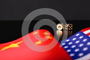 USA and China flags with dices on black table. International relations