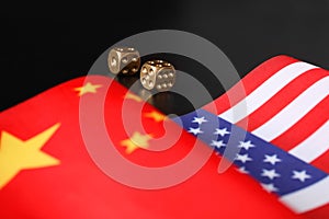 USA and China flags with dices on black table. International relations