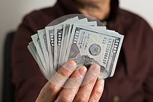 USA currency. Dollars. Front view of old woman`s hand handling b