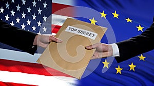 USA and European Union politicians exchanging top secret envelopes against flags