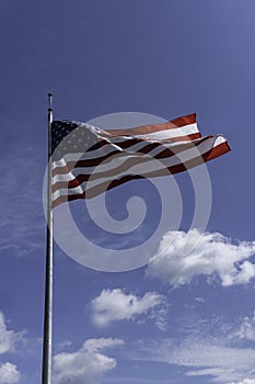 USA flag flying in the wind against a blue sky.