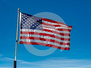 USA Flag waving against a bright blue sky.