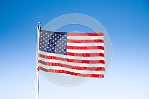 USA flag waving in the wind against blue sky on a sunny day