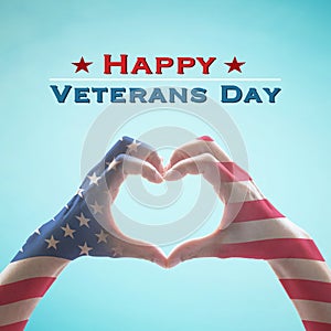 USA Happy veterans day with United Stated of America flag pattern on people`s hands in heart shape on blue sky greeting