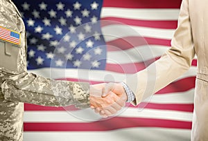 USA military man in uniform and civil man in suit shaking hands with adequate national flag on background - United States of Ameri