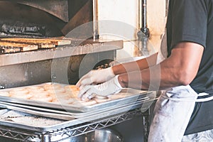 USA, New york: Traditional bagel bakery. Baker in the process of preparing authentic New York style bagels with sesame