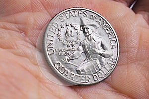 The USA quarter dollar coin with drummer lies in a man`s palm close up. Illustration on the theme of American patriotism and