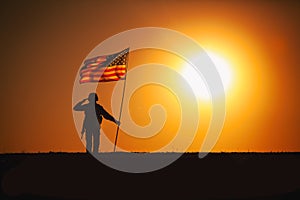 USA Soldier with flag saluting on sunset horizon