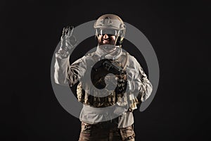 USA soldier in a military suit with a rifle smiles and shows the okay sign against a dark background, an American commando in