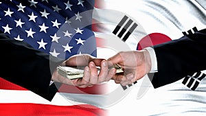 USA and South Korea officials exchanging money, flag background, business deal