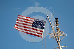 USA stars and stripes flag flying against a blue sky on top of a boat mast