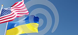 USA and Ukraine flags waving in the wind against a blue sky mockup with copy space. national symbols of the united states of