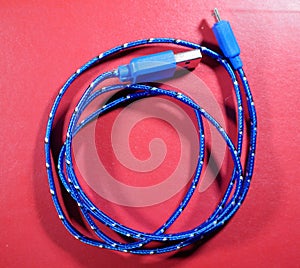 USB cable in blue braid with white dots on red background.