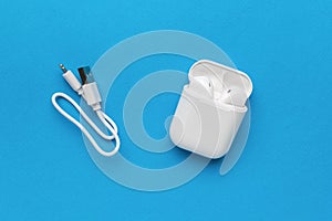 Usb cable and a box with wireless headphones on a blue background