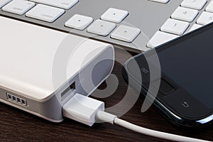 USB cable charger with energy bank on wooden table.