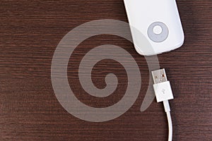 USB cable charger with energy bank on wooden table.