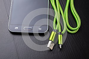 A usb cable for data transfer and phone charging. Telephone and accessories on the table