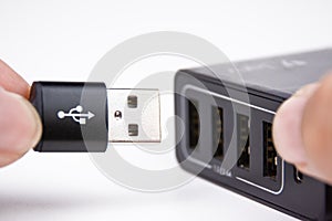 USB A charging cable in hand is plugging into a multi port mobile phone charger