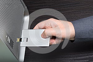 USB credit card flash drive connected by hand to a computer