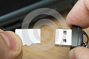 usb flash drive adapter micro sd card connection to laptop. micro sd card in man's hand