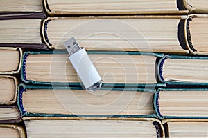 USB flash drive of a computer on the background of a stack of old paper books