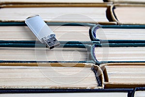 Usb flash drive on stack of paper old books. Keepers and carriers of information from different eras