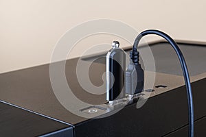 USB flash drive and USB cable both inserted into ports on the top of a computer tower case. Information transfer and storage