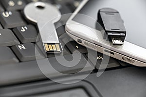 USB key and smartphone with micro USB flash drive on laptop keyboard