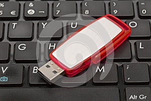 USB memory stick - Red flash drive on top of a dark computer keyboard