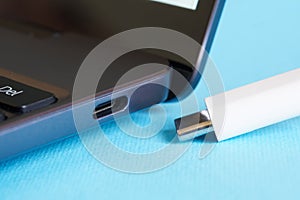 USB type-c port on a modern laptop - ultrabook and the corresponding plug on a blue background. Modern information technologies photo