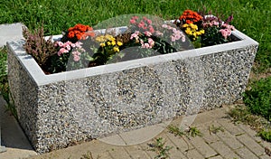 Use of annuals plants in concrete and brown plastic boxes near benches, polycarbonate bus stop. concrete parking for bicycles