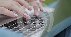 Use computer while sitting on the grass. Close-up of female hands typing on laptop at sunset in park