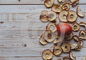 Use of dried fruits and vegetables. Dried apple chips and red fresh apples on a white wooden table. Organic natural wholesome food