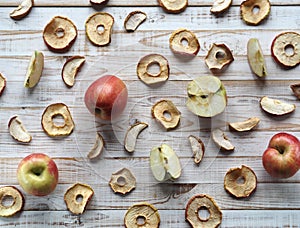 Use of dried fruits and vegetables. Dried apple chips and red fresh apples on a white wooden table. Organic natural wholesome food