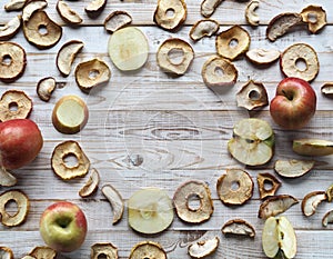 Use of dried fruits and vegetables. Dried apple chips and red fresh apples on a white wooden table. Organic natural wholesome food