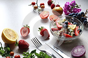 Use of fresh berries in vegetable salads-fruits and berries on the kitchen table near-glass dishes with vegetable salad, fork,