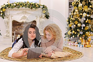 Use of modern gift gadget by two sisters lying on floor in brigh