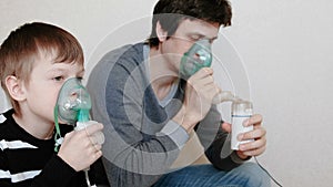 Use nebulizer and inhaler for the treatment. Man and boy inhaling through inhaler mask. Side view.