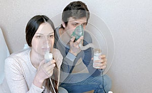 Use nebulizer and inhaler for the treatment. Man and woman inhaling through inhaler mask. Closeup front view.