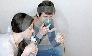 Use nebulizer and inhaler for the treatment. Man and woman inhaling through inhaler mask. Closeup side view.